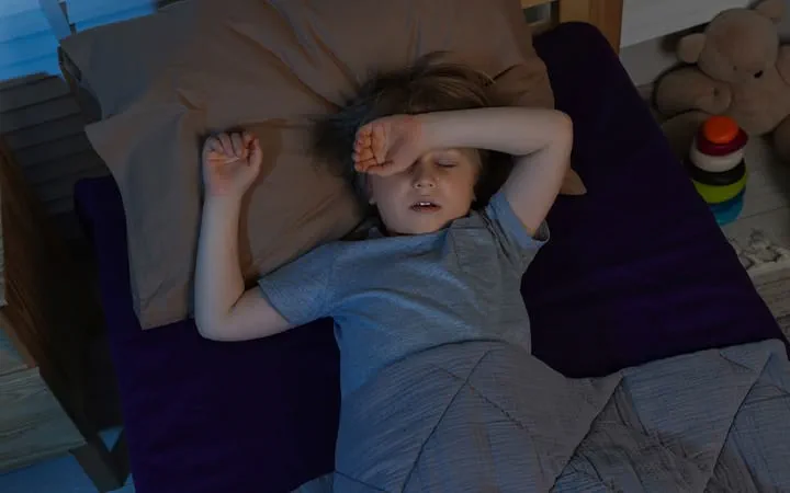 A young child sleeping restlessly at night with arm over face